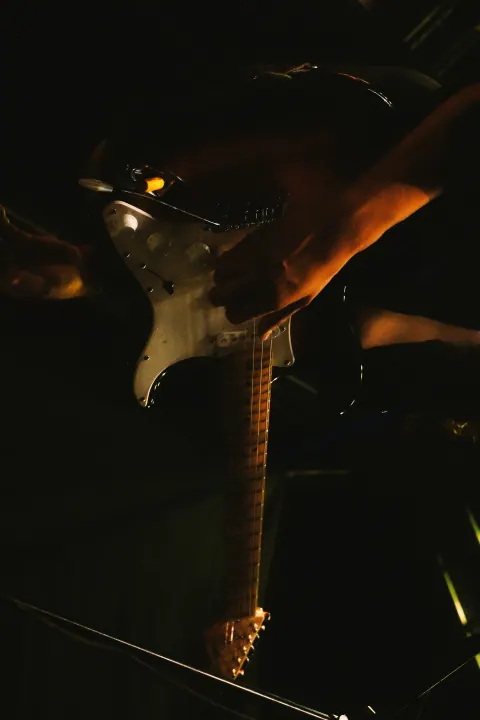 Detalle de una guitarra eléctrica y las manos del músico durante el concierto.